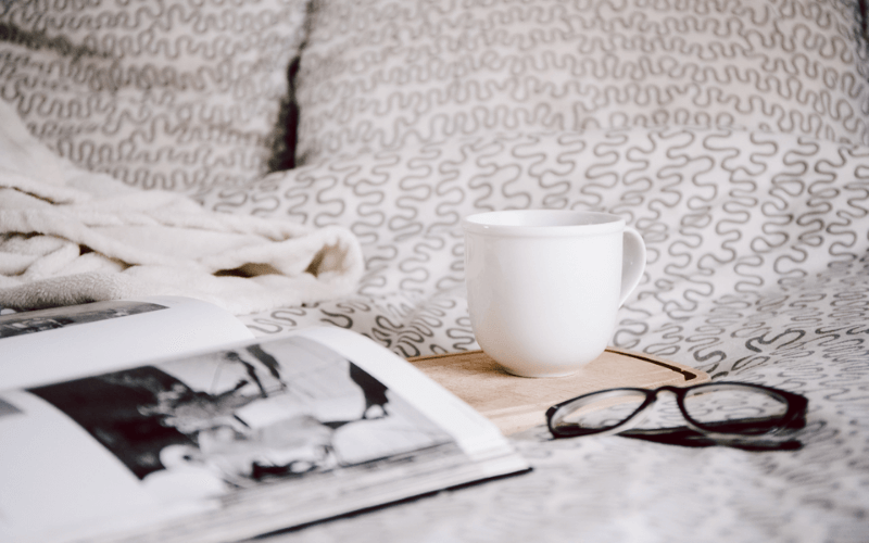 magazine, coffee and glasses on a bed